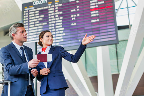 Fotografía Mature businessman showing his boarding pass with the attractive airport staff