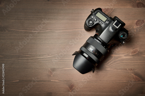 top view of a modern digital SLR with attached zoom lens and hood on wooden table