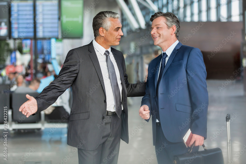 Mature businessman gesturing while talking to business partner in airport Mature businessman gesturing while talking to business partner in airport