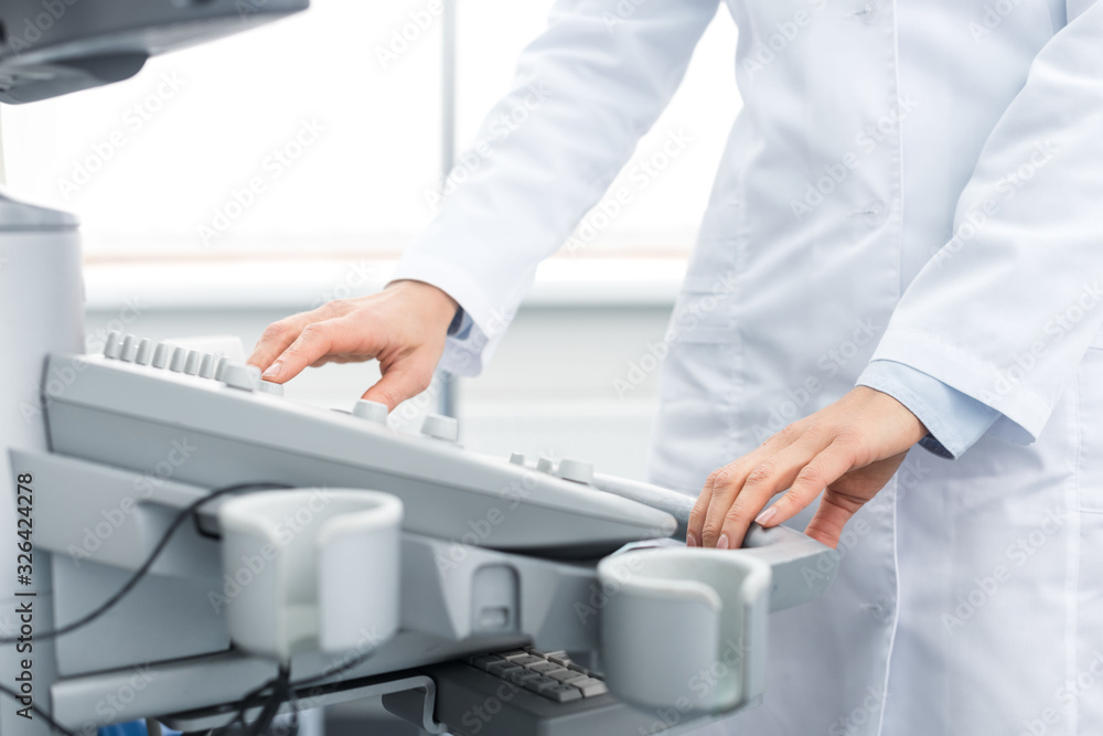 cropped view of doctor in white coat working with ultrasound scanner in clinic cropped view of doctor in white coat working with ultrasound scanner in clinic