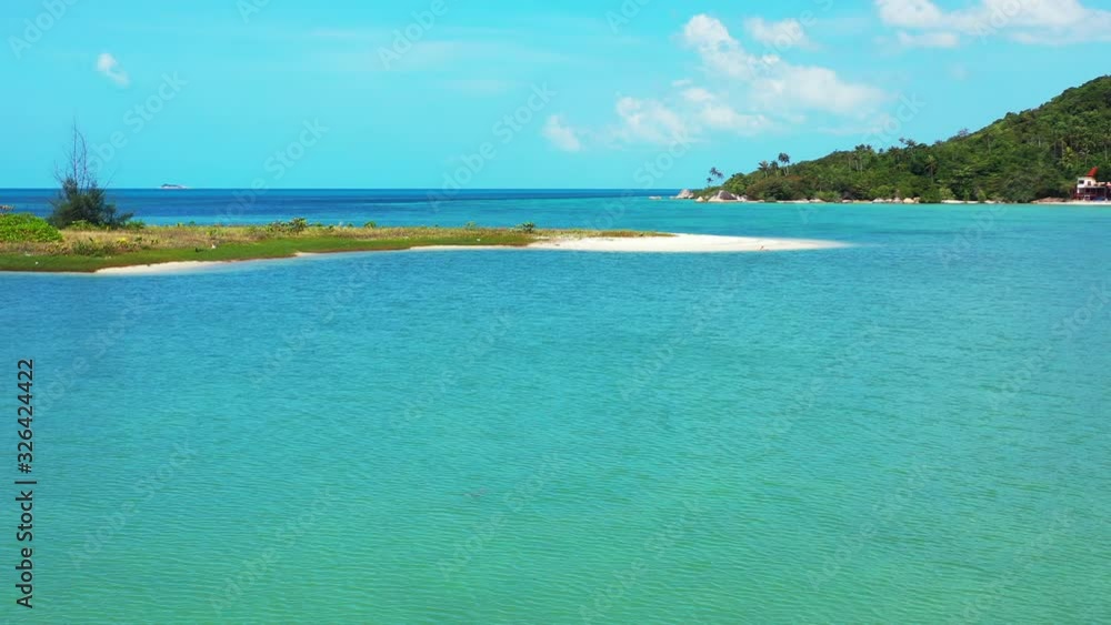Peaceful calm turquoise lagoon with tiny island in the middle of beautiful bay of tropical island under bright sky with white clouds, Thailand Peaceful calm turquoise lagoon with tiny island in the middle of beautiful bay of tropical island under bright sky with white clouds, Thailand