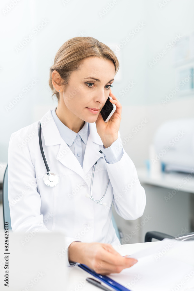 professional doctor holding talking on smartphone in clinic professional doctor holding talking on smartphone in clinic