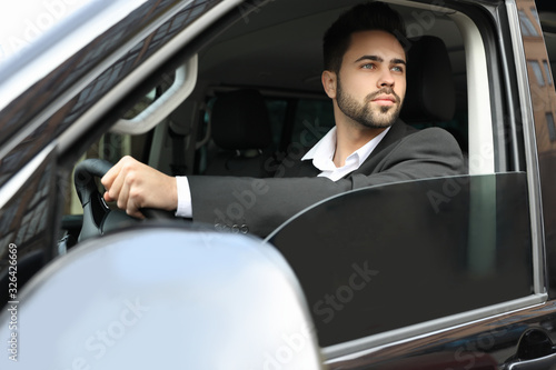 Handsome young man driving his modern car