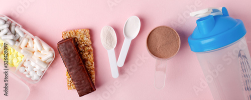 Protein powder, scoop, energetic musli bars, vitamin pills, gainer, shaker on pink background - concept of sport diet, healthcare, nutrition fit fitness food, copyspace