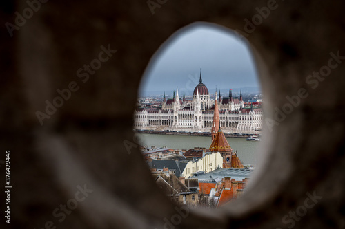 look through a hole in fishermans bastion on Buda Castle Hill, Budapest with Hungarian Parliament Building