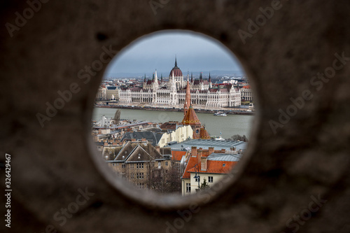 Hungarian Parliament Building seen through a hole in fishermans bastion on Buda Castle Hill, Budapest with