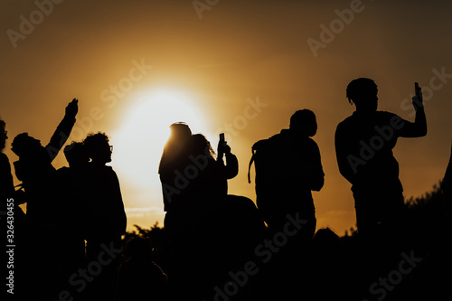 FLORENCE, ITALY - MARCH 05, 2019: Silhouettes of people taking pictures of the sunset with mobile phones and selfie stick on a sunset in Florence, Italy. Rear view. © eduard