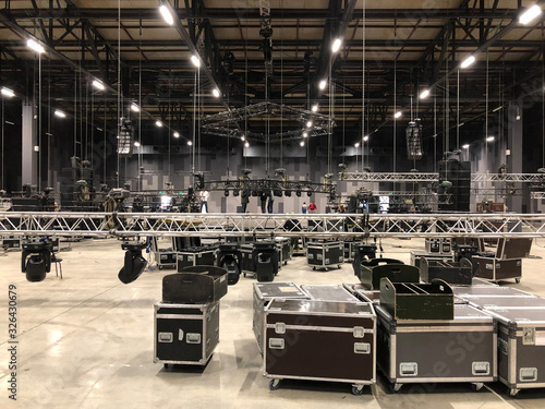 Installation of professional sound, light, video and stage equipment for a concert. Stage lighting equipment is clamped on a truss for lifting. Flight cases with cables. photo