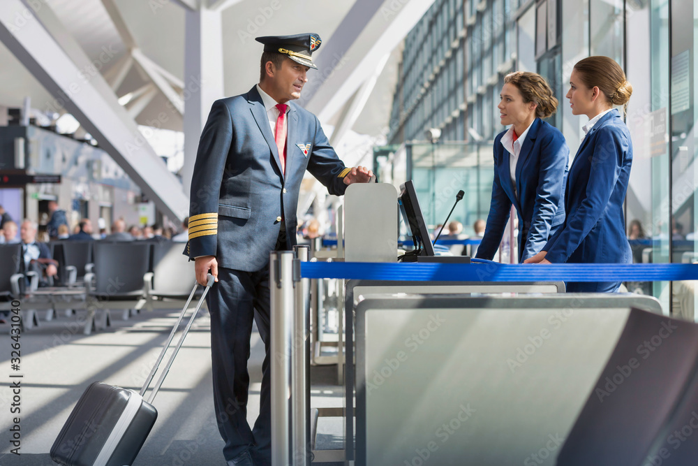 Portrait of mature pilot talking with the airport staffs in boarding gate Portrait of mature pilot talking with the airport staffs in boarding gate