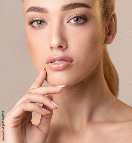 Attractive Woman Touching Lips Posing On Beige Studio Background  Cropped