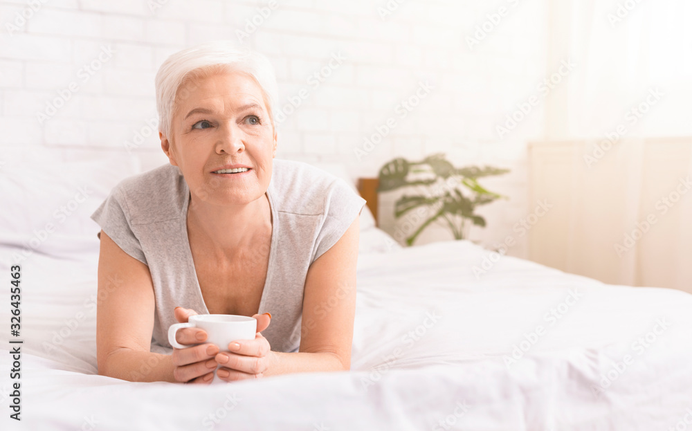 Senior lady enjoying hot fresh coffee, resting in bed Senior lady enjoying hot fresh coffee, resting in bed