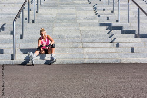 Young attractive woman adjusting safety gear while wearing rollerblades