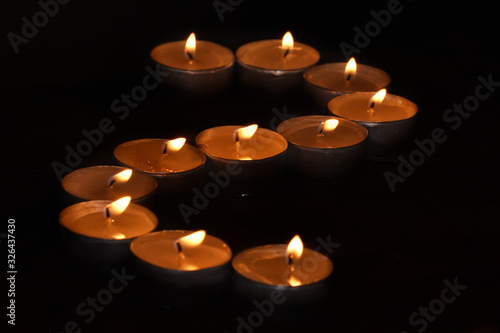 Many small flat candles in small aluminum candle holders