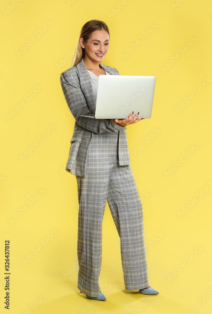 Beautiful woman using laptop on yellow background Beautiful woman using laptop on yellow background