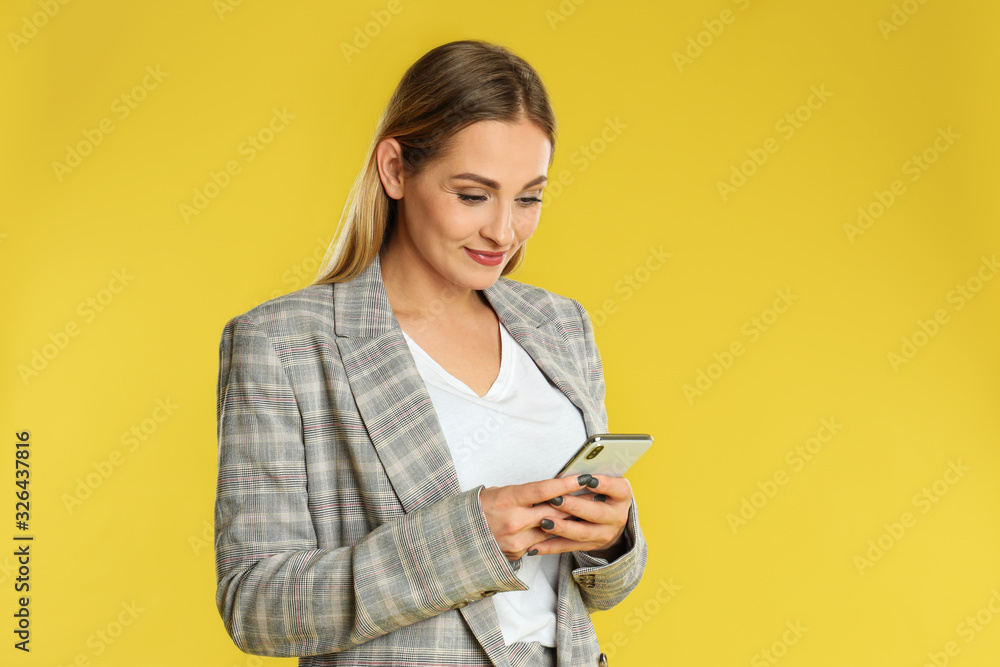 Beautiful woman using smartphone on yellow background Beautiful woman using smartphone on yellow background