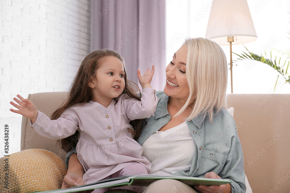 Granddaughter and grandmother reading book at home Granddaughter and grandmother reading book at home
