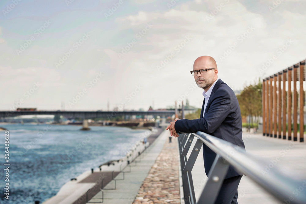 Portrait of thoughtful mature businessman leaning on railing Portrait of thoughtful mature businessman leaning on railing