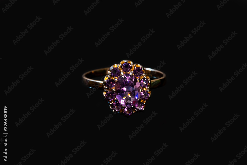 Beautiful golden ring with purple gemstone isolated on black background Beautiful golden ring with purple gemstone isolated on black background