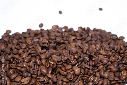 Roasted coffee beans pile and flying coffee beans isolated on white background. Selective focus.