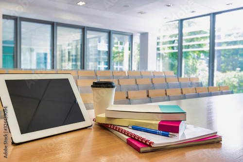 Photo of digital tablet, books and cup of coffee on table in classroom photo