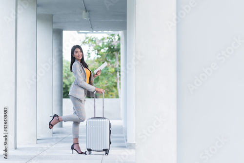 Happy business woman is traveling with luggage in airport..