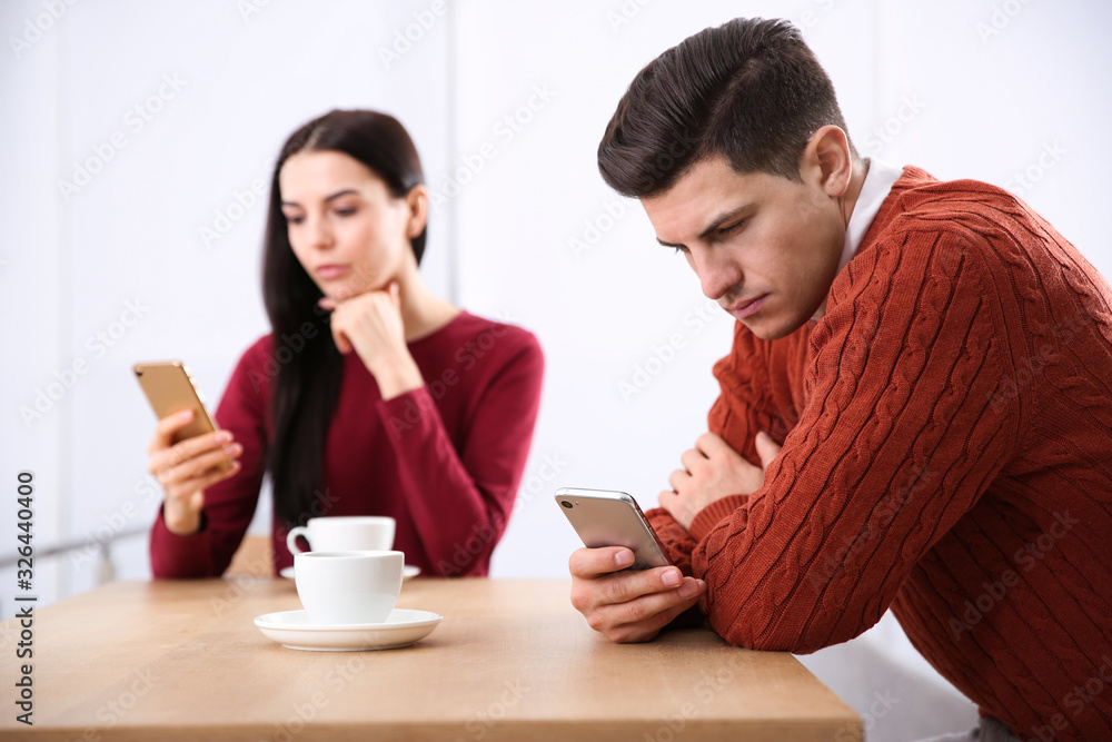 Couple addicted to smartphones ignoring each other in cafe. Relationship problems Couple addicted to smartphones ignoring each other in cafe. Relationship problems
