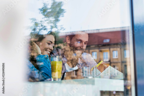 Young attractive couple smiling while looking at the menu in restaurant