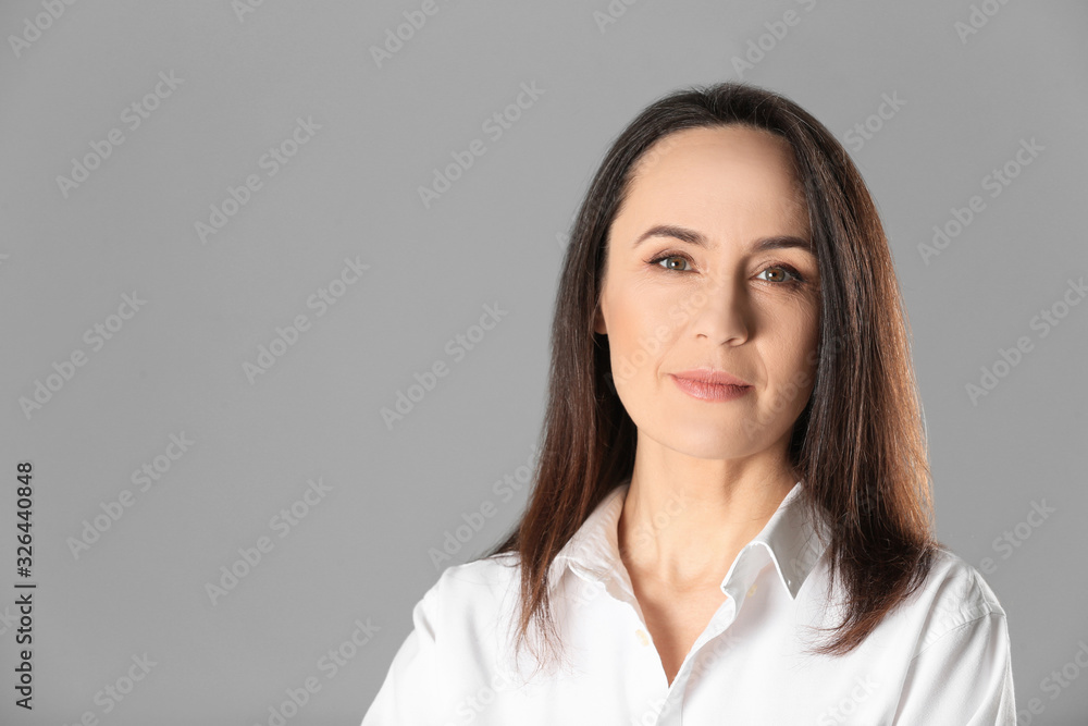 Portrait of beautiful mature woman on grey background. Space for text Portrait of beautiful mature woman on grey background. Space for text