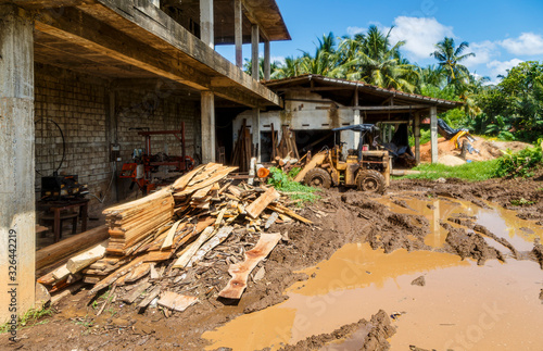 Asian sawmill in tropics, mud, puddles, tractor, Sri Lanka, day, Sunny