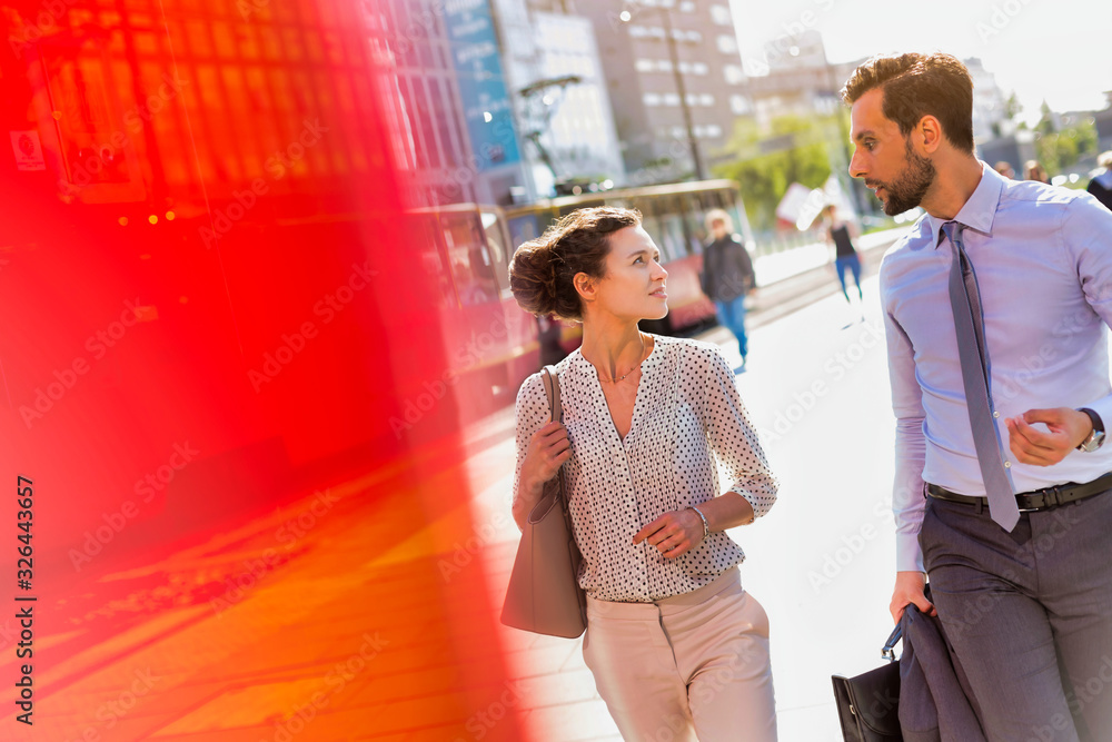 Businessman and businesswoman walking while discussing plans before meeting