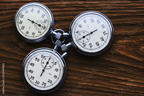 Three mechanical stopwatches on a wooden background.