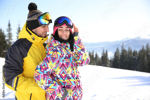 Young couple at ski resort, space for text. Winter vacation