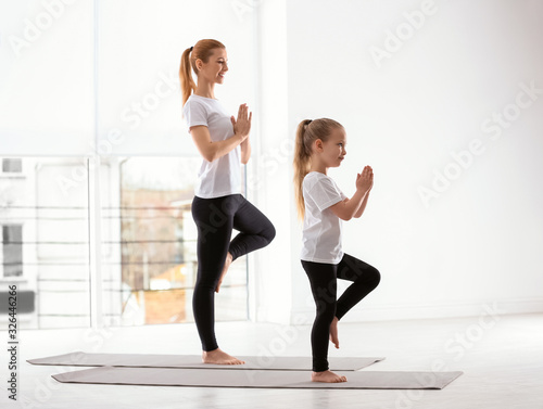 Mother and daughter in matching sportswear doing yoga together at home