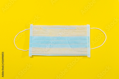 disposable medical mask on a yellow background,