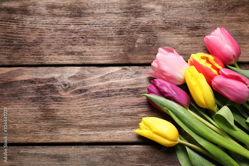 Beautiful spring tulips on wooden table, flat lay. Space for text