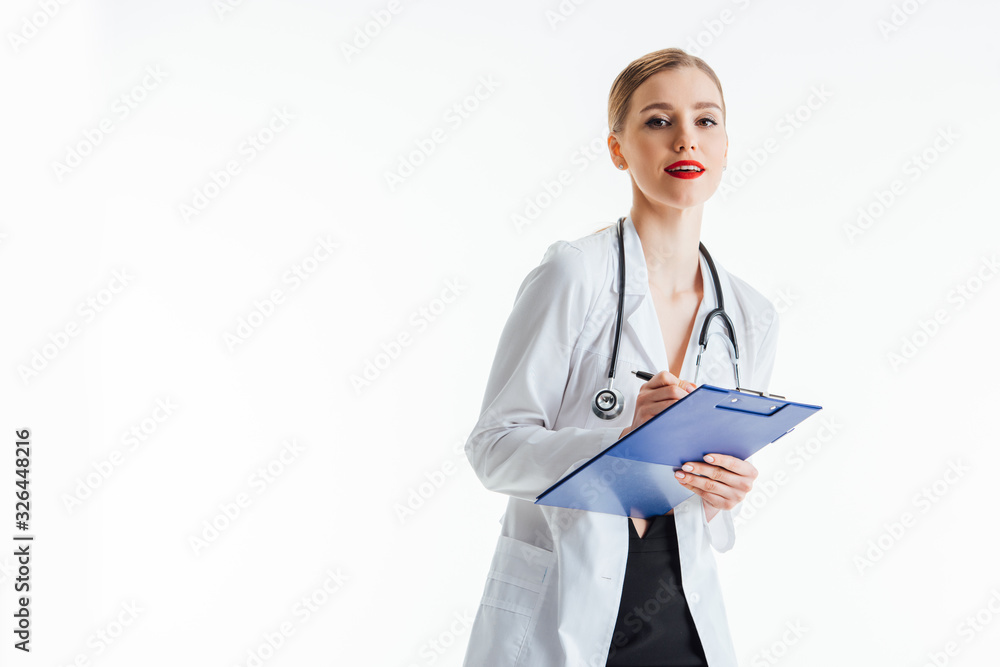 happy and sexy nurse in white coat writing prescription while holding clipboard isolated on white happy and sexy nurse in white coat writing prescription while holding clipboard isolated on white