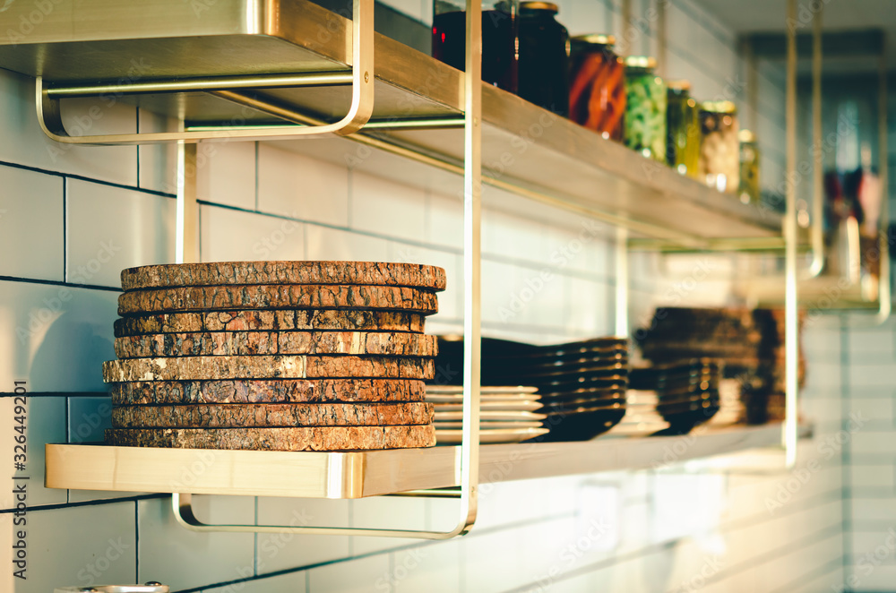 Wooden cutting boards stacked on the shelf in a modern kitchen .and there is a dish that is out of focus Placed on the same length