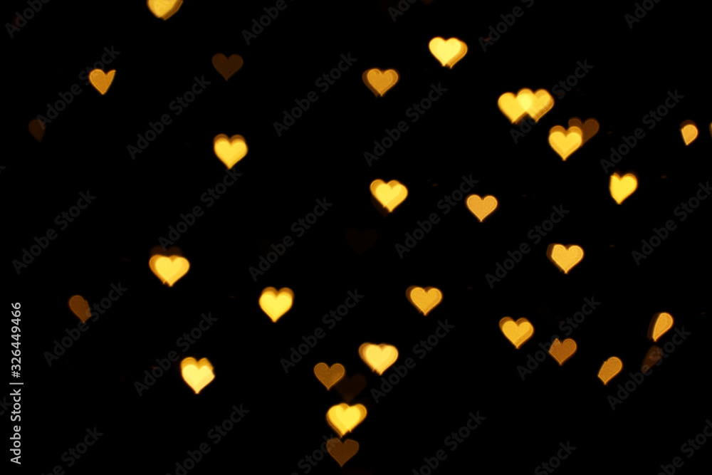 Blurred view of heart shaped lights on black background. Bokeh effect