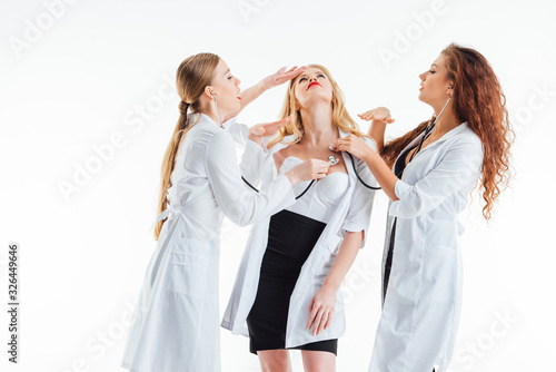 sexy nurses examining young woman feeling unwell isolated on white