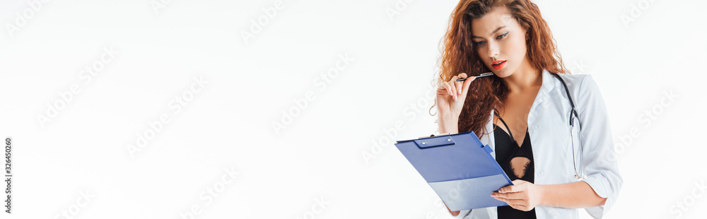 panoramic shot of curly and sexy nurse holding pen and looking at clipboard isolated on white panoramic shot of curly and sexy nurse holding pen and looking at clipboard isolated on white