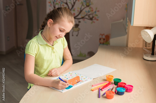 Beautiful teenage girl drawing at the table