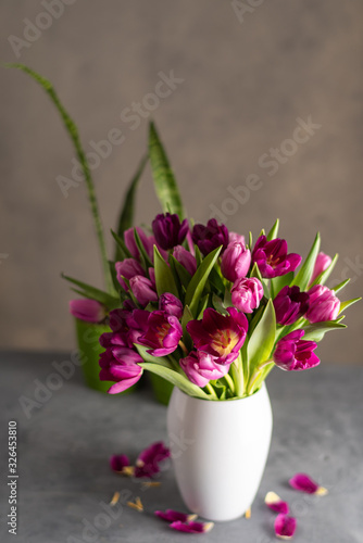 bouquet of tulips in white vase on stone grey background