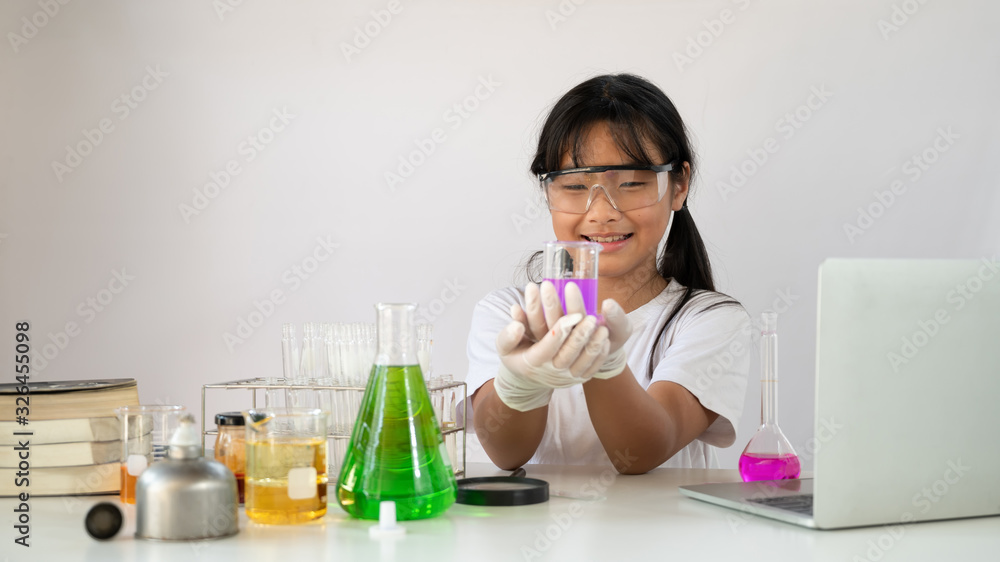 Young adorable girl in safety glasses and gloves holding a flasks for chemistry while doing a scientist experiment at the modern laboratory with isolated white background. Young adorable girl in safety glasses and gloves holding a flasks for chemistry while doing a scientist experiment at the modern laboratory with isolated white background.
