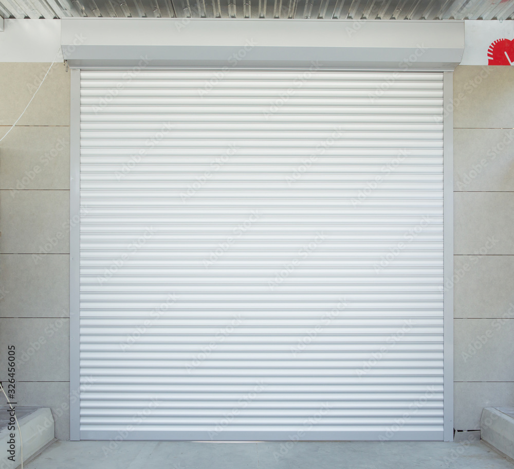 Fototapeta premium Shutter door or roller door and concrete floor outside .White Automatic shutters in a house . gates in the garage . Automatic Electric Roll-up Gate Or Push-up Door In The Modern Building .
