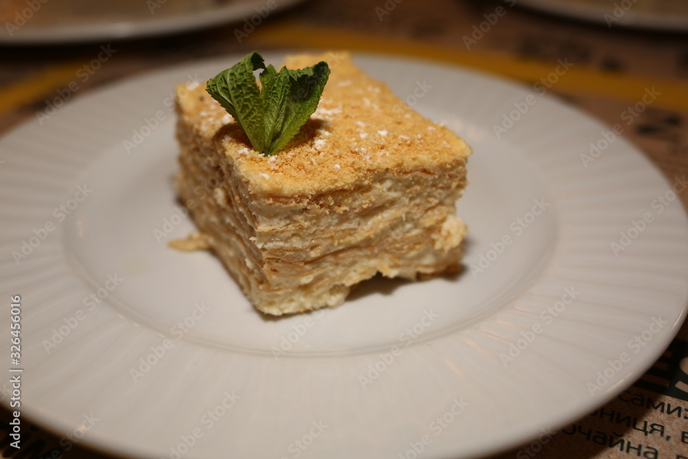 a piece of cake Napoleon lies on a plate in a restaurant, close-up