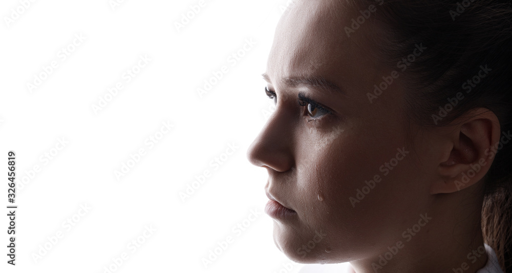 Beautiful young woman with sad big eyes crying. White background. Free space for text. Tear on cheek of unhappy female. Beautiful young woman with sad big eyes crying. White background. Free space for text. Tear on cheek of unhappy female.