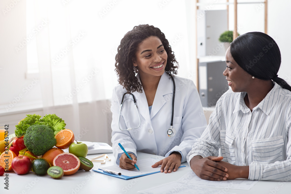 Friendly afro lady nutritionist making patient anamnesis at clinic - obrazy, fototapety, plakaty 