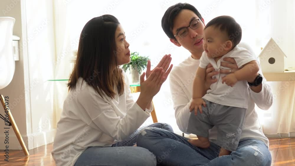 Happy Asian family of three, young father and mother playing games and clapping hands with baby boy child at home, parents enjoying family time. Happy Asian family of three, young father and mother playing games and clapping hands with baby boy child at home, parents enjoying family time.