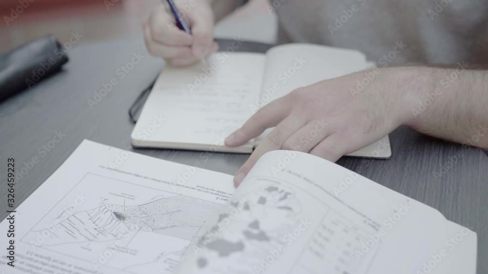 A male student taking notes by hand A male student taking notes by hand