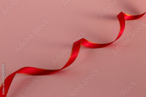 Red ribbon on a pink background. Selective focus.
